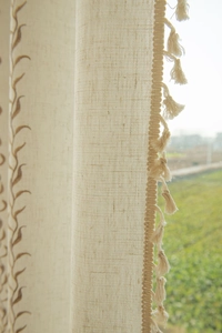 Detail of cream tassel trim and floral vine embroidery on cotton linen garden curtains