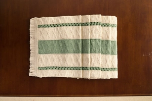 Detail of Nordic woven placemat with cream and green block design and fringed edges