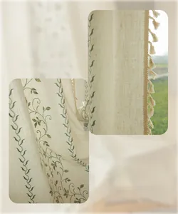 Detail of cream linen curtain featuring green leaf embroidery and beige tassel fringes