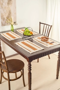 Set of four woven rectangle placemats with orange stripes and elegant tassels on dark wood