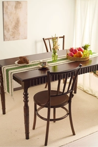 Detail of forest green and off-white striped table runner with fringe on a wooden table