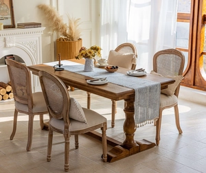 Detailansicht eines französischen Esssets mit Massivholztisch und Rattanstühlen