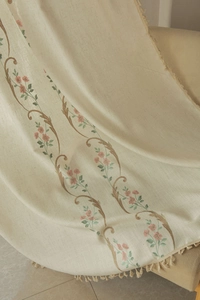 Detail view of American rural floral embroidery on cream linen curtain with fringe trim