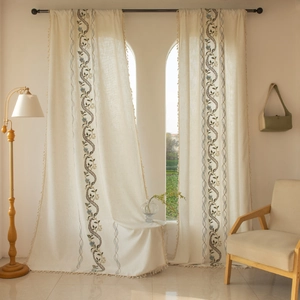 Detail of Nordic floral embroidery on linen-textured curtains with elegant tassel fringe