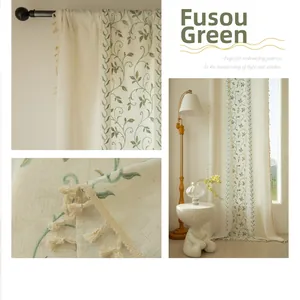 Detail of green vine embroidery on beige linen curtain with short tassel fringe