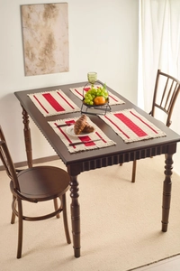 Close-up of red and beige striped woven placemats with fringe on a dark wood table