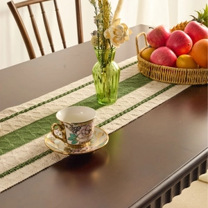 Nordic green and white striped table runner with woven texture and tassels on wooden table