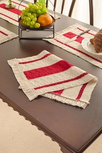 Detail of red and white striped woven placemat with tassels on a dark wood table