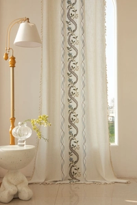 Detail of bohemian floral embroidery and tassel fringe on beige linen curtain fabric