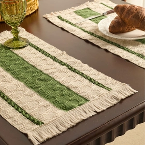 Minimalist woven table runner with green stripes and fringe tassels on dark wood