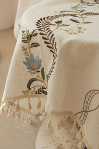 Close-up of embroidered blue floral pattern and tassel edge on linen fabric
