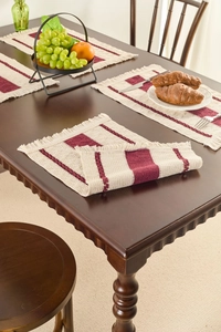 Detailed top-down view of a woven cream placemat with burgundy stripes and tassel edges