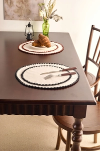 Detail of round cotton linen placemats with crochet wavy edges in black and brown