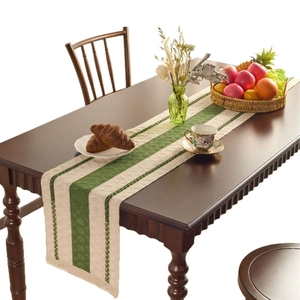 Nordic woven table runner with green stripes and tassels on a dark wood dining table