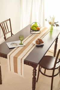 Dettaglio del runner da tavola intrecciato con strisce boho, motivi traforati e frange