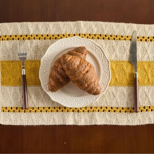 Nordic woven table runner with striped yellow and beige patterns and festive tassels