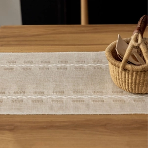 Beige linen table runner with hollow weave patterns and fringe details for home decor