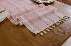 Detail eines altrosa Tischläufers mit weißen Stickereien und beigen Quasten