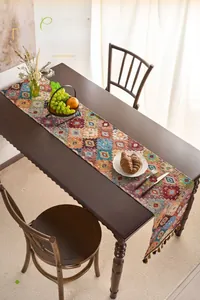 Detailed view of bohemian table runner with orange geometric patterns and decorative tassels