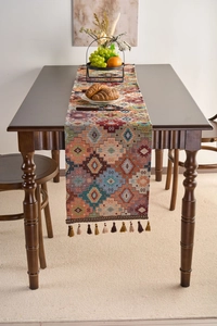 Macro detail of bohemian table runner with orange geometric patterns and handmade tassels