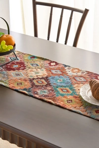 Close-up of bohemian orange geometric woven table runner with fringe and food props