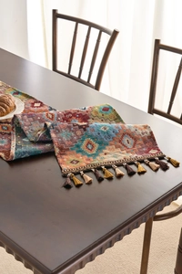 Detail of bohemian geometric jacquard table runner with decorative tassels on wood table