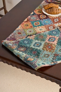 Detail of colorful geometric diamond pattern woven table runner with boho tassels