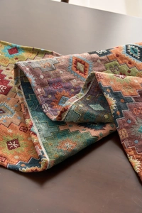 Macro detail of Bohemian geometric woven table runner with orange tassels and thick texture