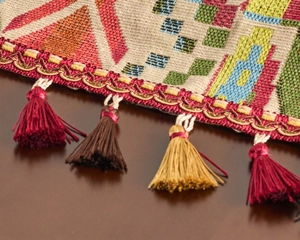 Close-up of geometric jacquard table runner with colorful tassels and wave trim