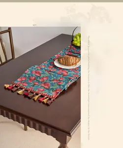 Close-up of vintage floral jacquard table runner with decorative tassels on wood table