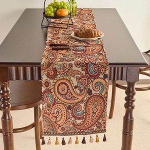 Runner da tavola etnico jacquard con motivi paisley e nappe su tavolo in legno