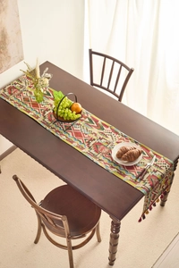 Detail of bohemian geometric table runner with tassels on a dark wooden table