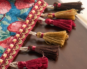 Detail of jacquard table runner with red cherry pattern and three-color silk tassels