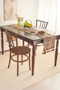 Detail of bohemian geometric table runner with multi-color weaving and colorful tassels