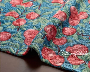Macro view of blue jacquard table runner featuring red cherry patterns and woven textures