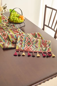 Detail of ethnic geometric woven table runner with colorful tassels on a wooden table