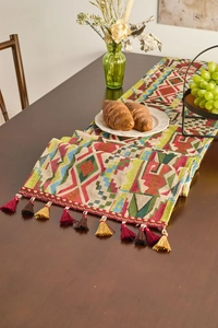 Close-up of geometric jacquard table runner with multi-color fringe and woven tassels