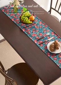 Detail view of American style table runner with red cherry jacquard on a dark wood table