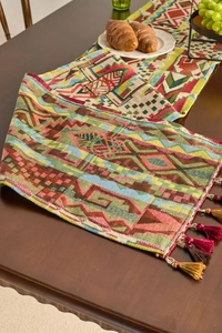 Close-up of geometric woven table runner with colorful tassels on a dark wooden table