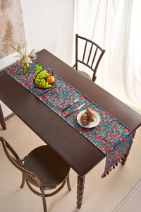 Detailed view of jacquard table runner with red berries pattern and colorful tassels