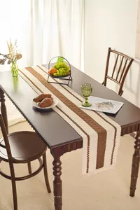 Close-up of beige and brown striped linen table runner on a dark wood dining table