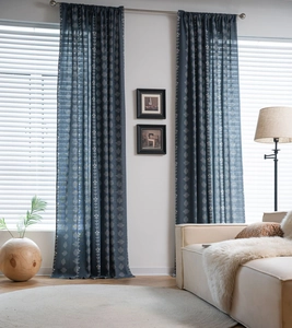 Detail of sage green semi-sheer curtain with white floral print in a cozy living room