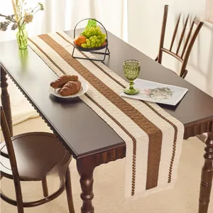 Close-up of Nordic style striped table runner with handmade tassels on dark wood table