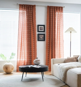 Close-up of burnt orange linen curtains with white geometric patterns in a modern living room