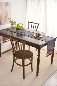 Close-up of American rural style table runner with red cherry jacquard and fringe details