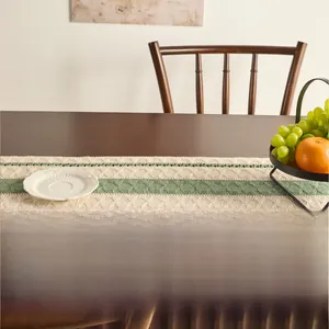 Close-up of knit table runner showing green and beige stripe patterns and crochet texture