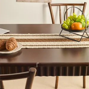 Close-up of a striped woven table runner in beige and brown on a dark wood table