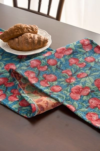 Detail of blue American country table runner showing red cherry jacquard woven texture