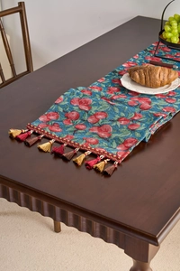 Detail of blue table runner with red cherry jacquard pattern and elegant colorful tassels
