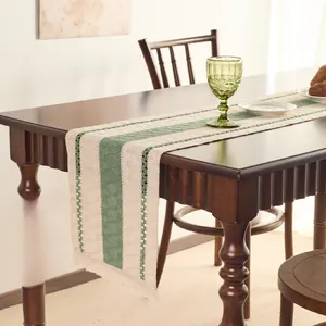 Close-up detail of woven table runner with green stripes and decorative fringe tassels